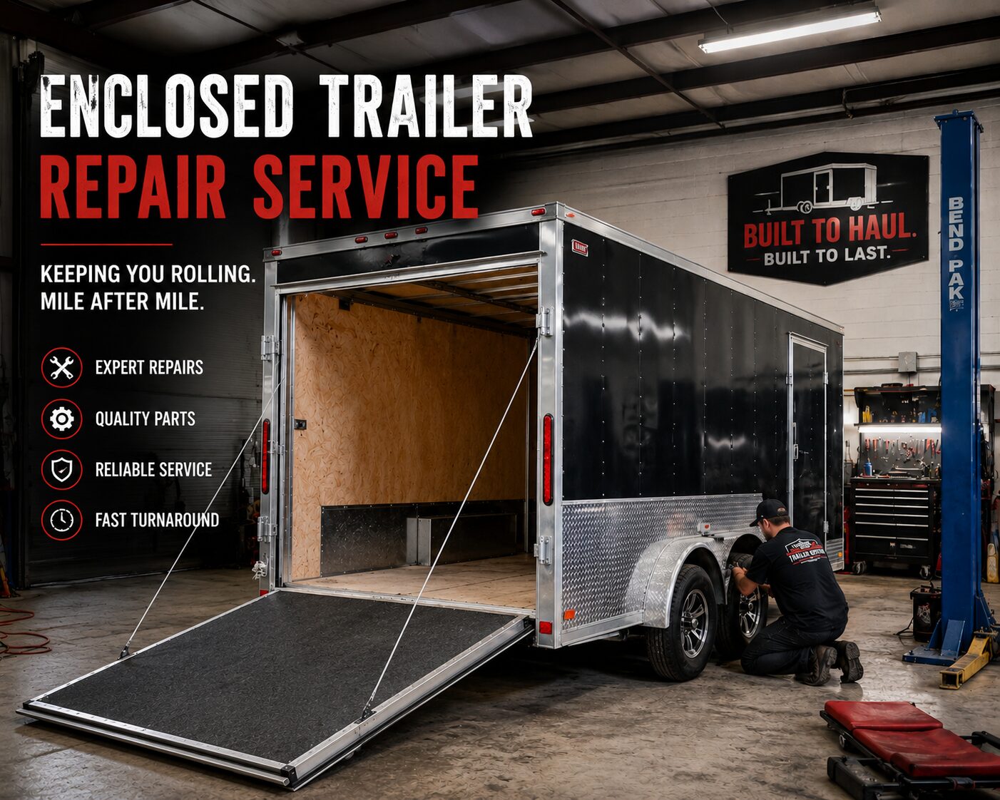 Technician kneels at the rear wheel of an enclosed trailer in a workshop, ramp down and tools nearby, with repair service signage on the wall above.