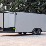 Enclosed gray cargo trailer with black trim and Haulmark branding, a tandem axle, parked on a gravel lot.